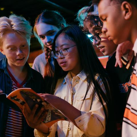 Teens standing around a book