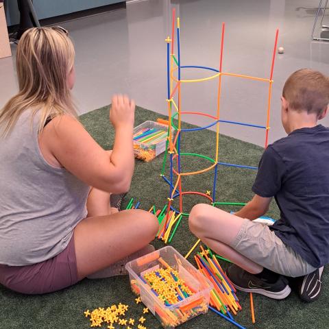 Women and child building with straws