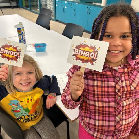 Two children holding up cards that say BINGO