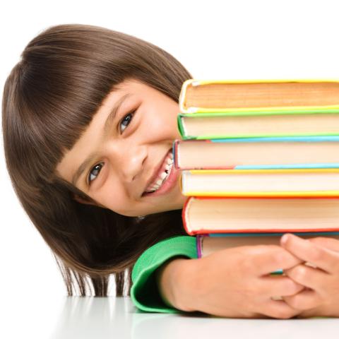 Smiling girl peeking around stack of books