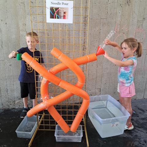 Kids playing with water in a orange tube