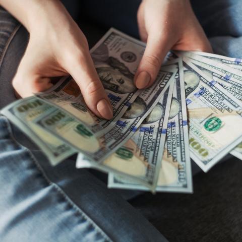 Hands holding a fan of $100 bills.