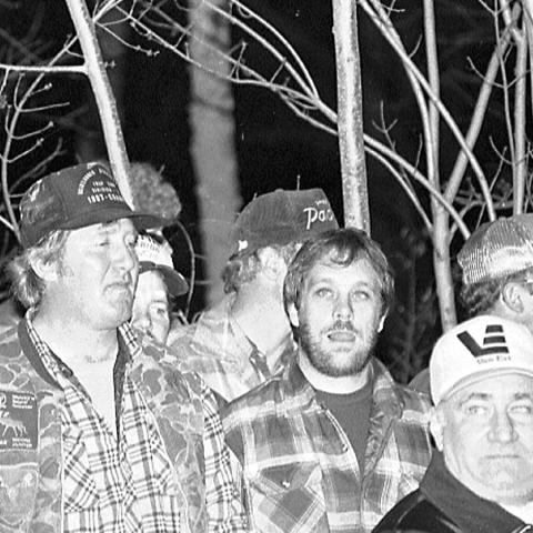 An old photo of Wisconsin men gathered outside at night. 