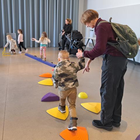 Children playing on stepping stone toys, assisted by adult