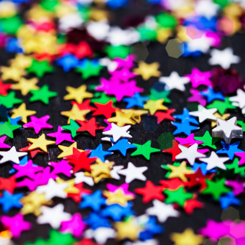 A photograph of colorful confetti in the shape of stars.
