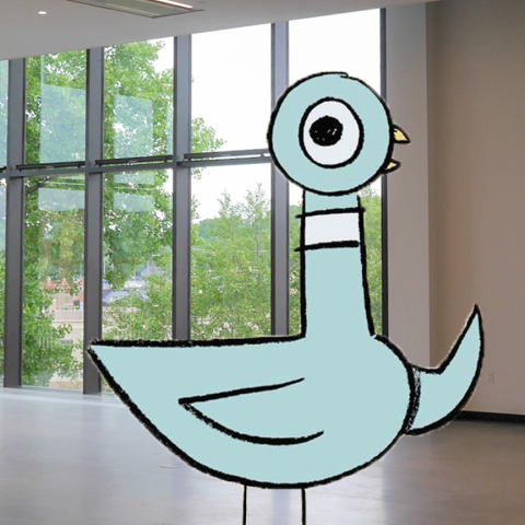 A picture of Mo Willem's Pigeon character standing in a library room.
