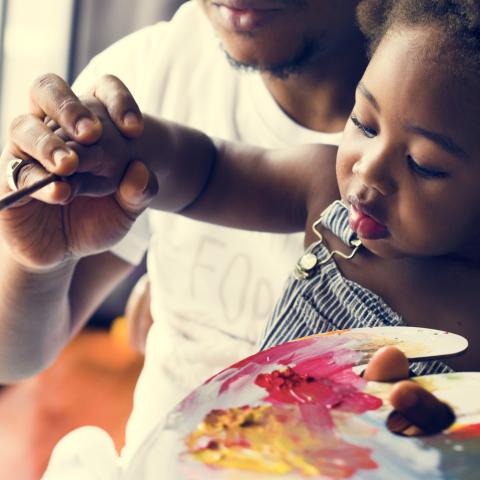 Dad helping young child paint.