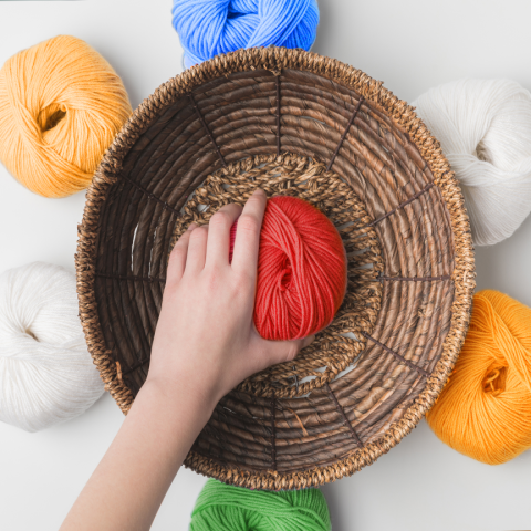A photograph of a child's hand clutching colorful yarn.