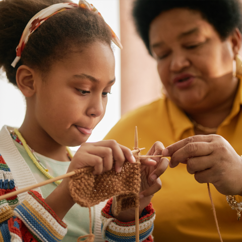 A photo of a child learning to knit.