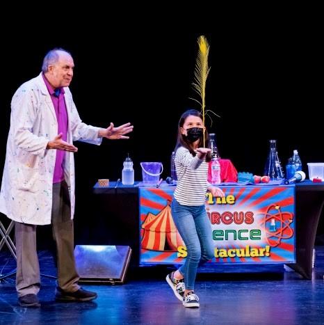 Scientist and child balancing feather on hand