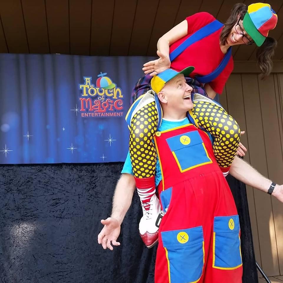 Man and woman wearing bright colors. Woman is on man's shoulders.