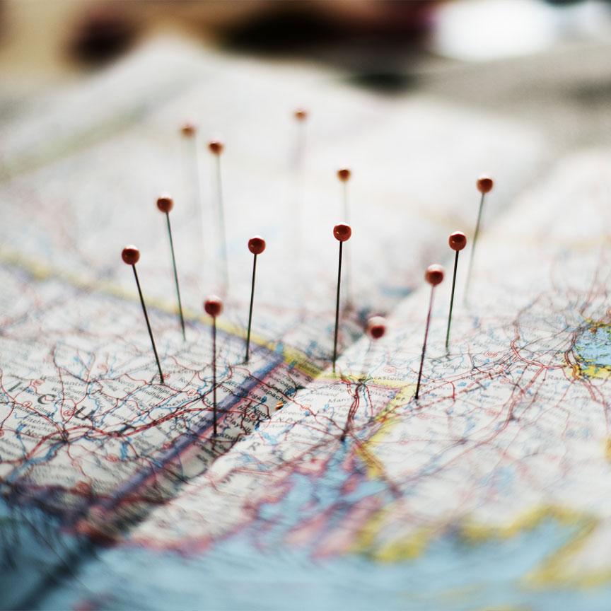 A photograph of a map that has pins pierced into it to mark specific locations.