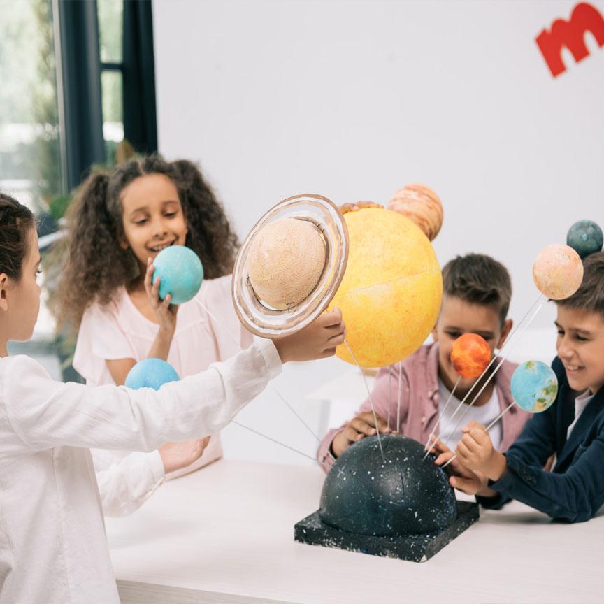 A photograph of four school-aged children participating in a science class.