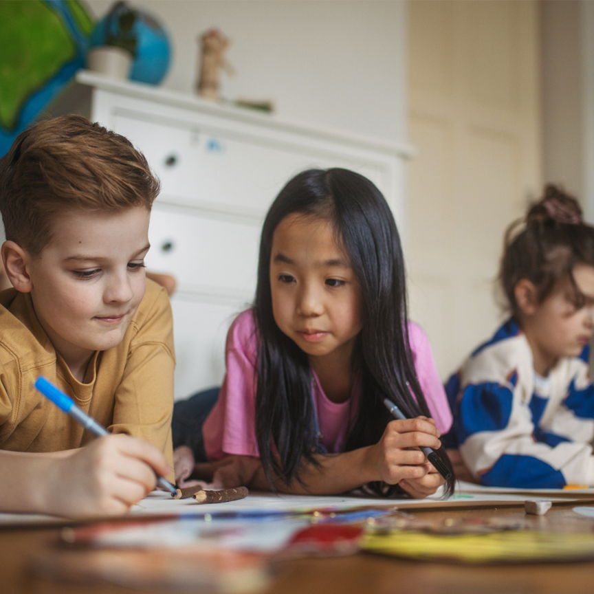 A photograph of three children working on an art project.