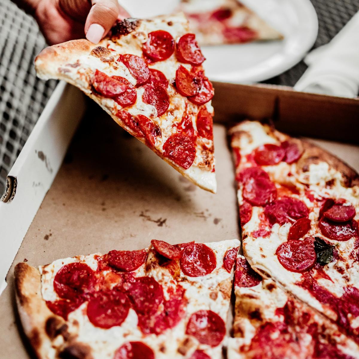 Pepperoni pizza, with someone holding up a slice.