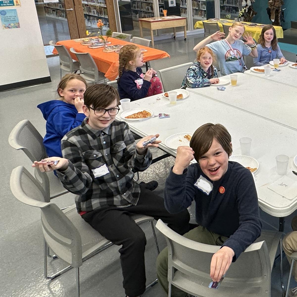 Kids sitting at a table, hamming it up for the camera.